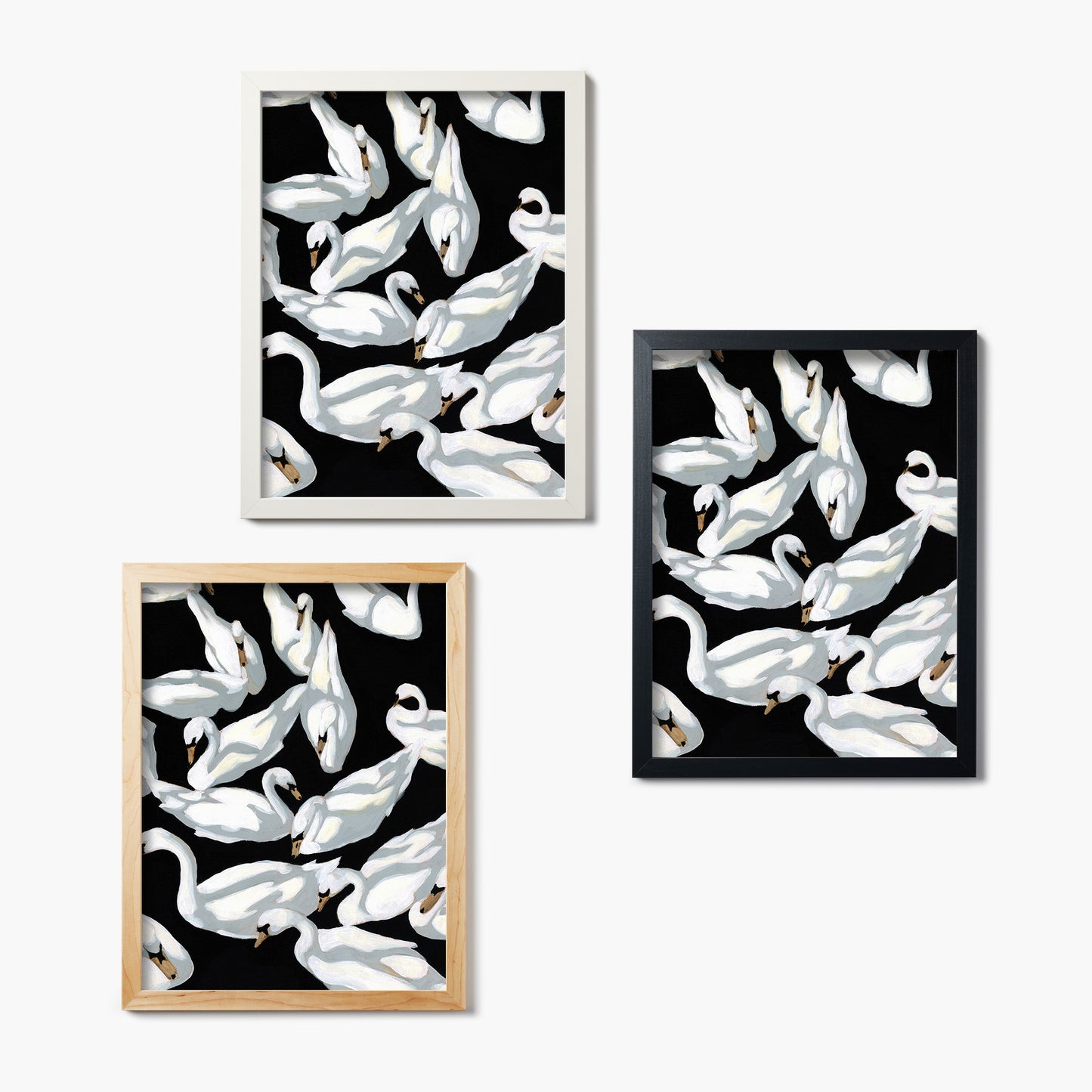 Set of three framed glass prints of white swan designs on black backgrounds.