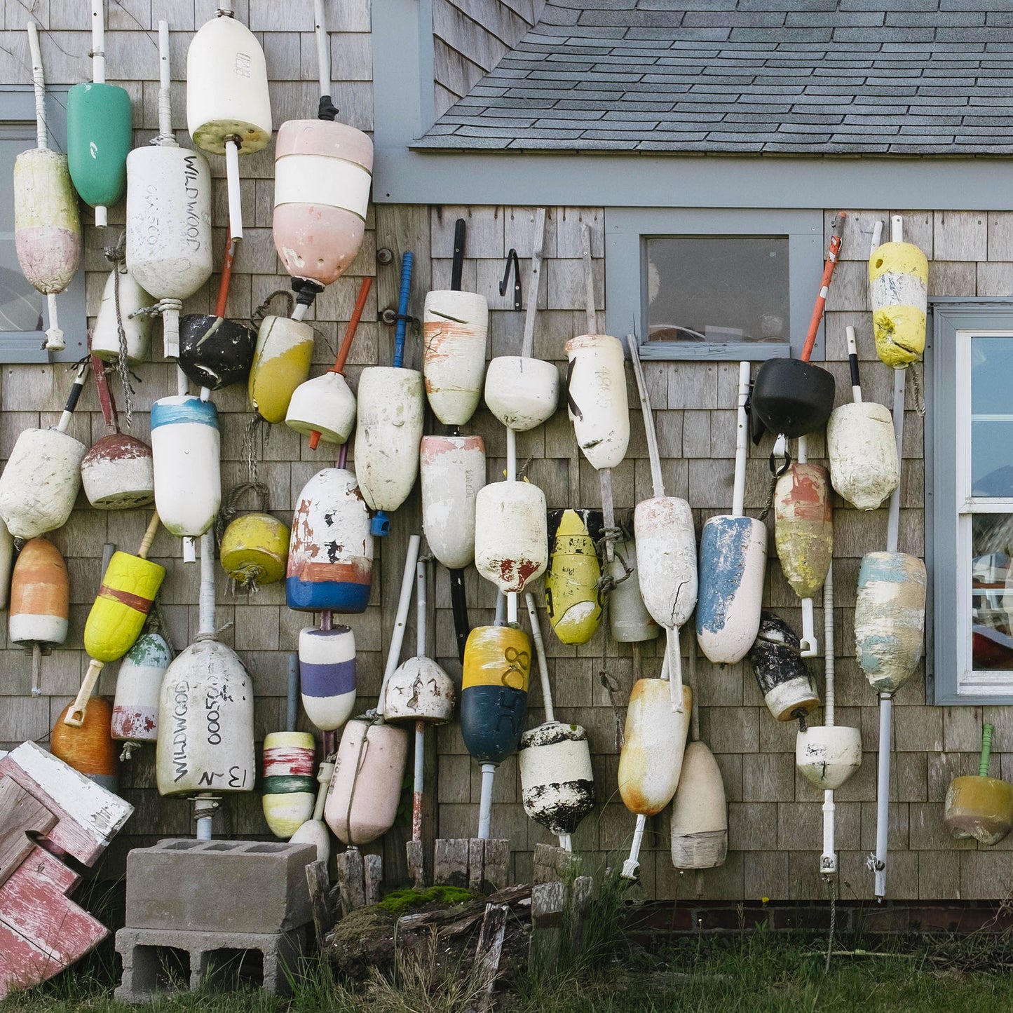 Close up of a collection of colorful buoys attached to the exterior of a house.