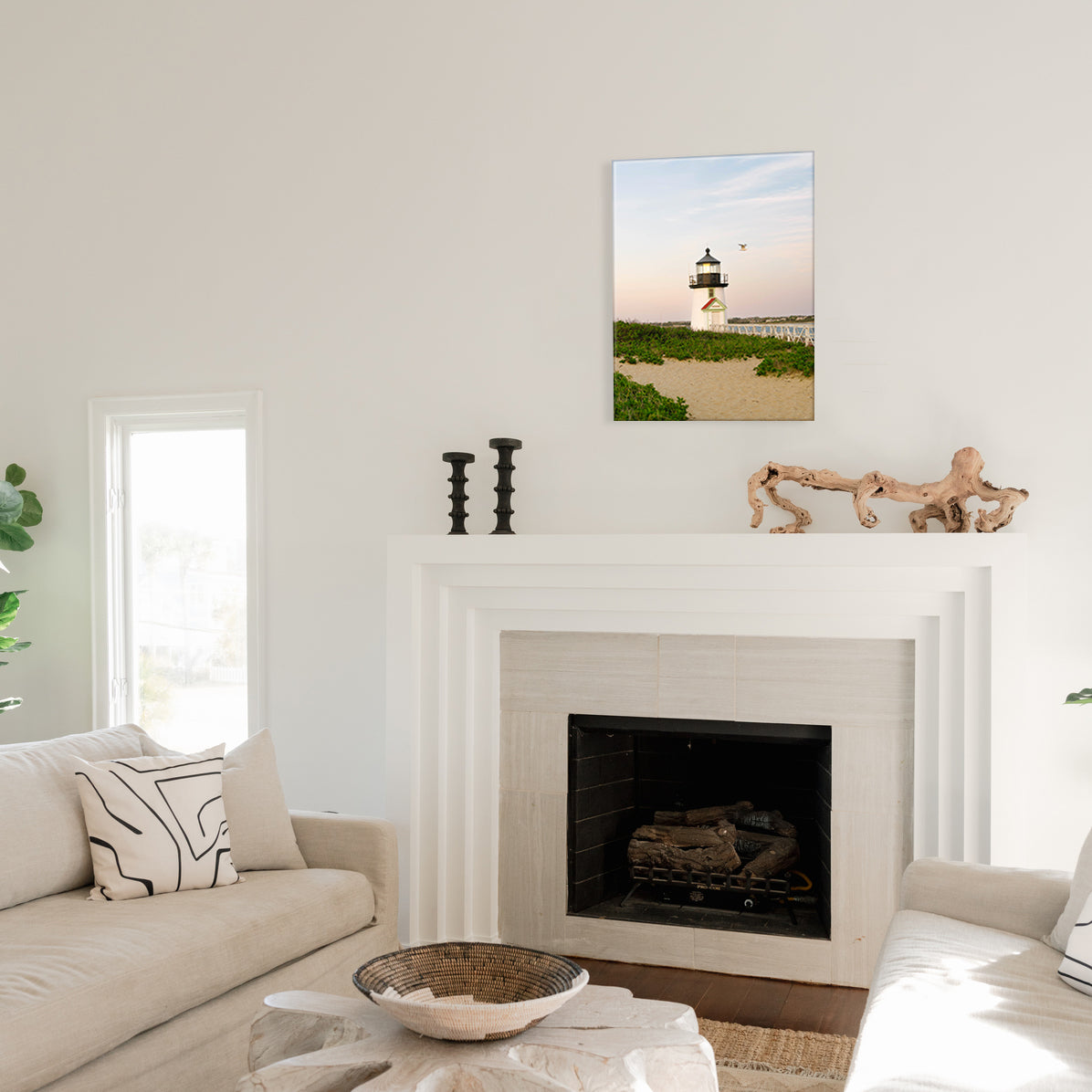 Living room with a fireplace, couch, and a glass print of a lighthouse.
