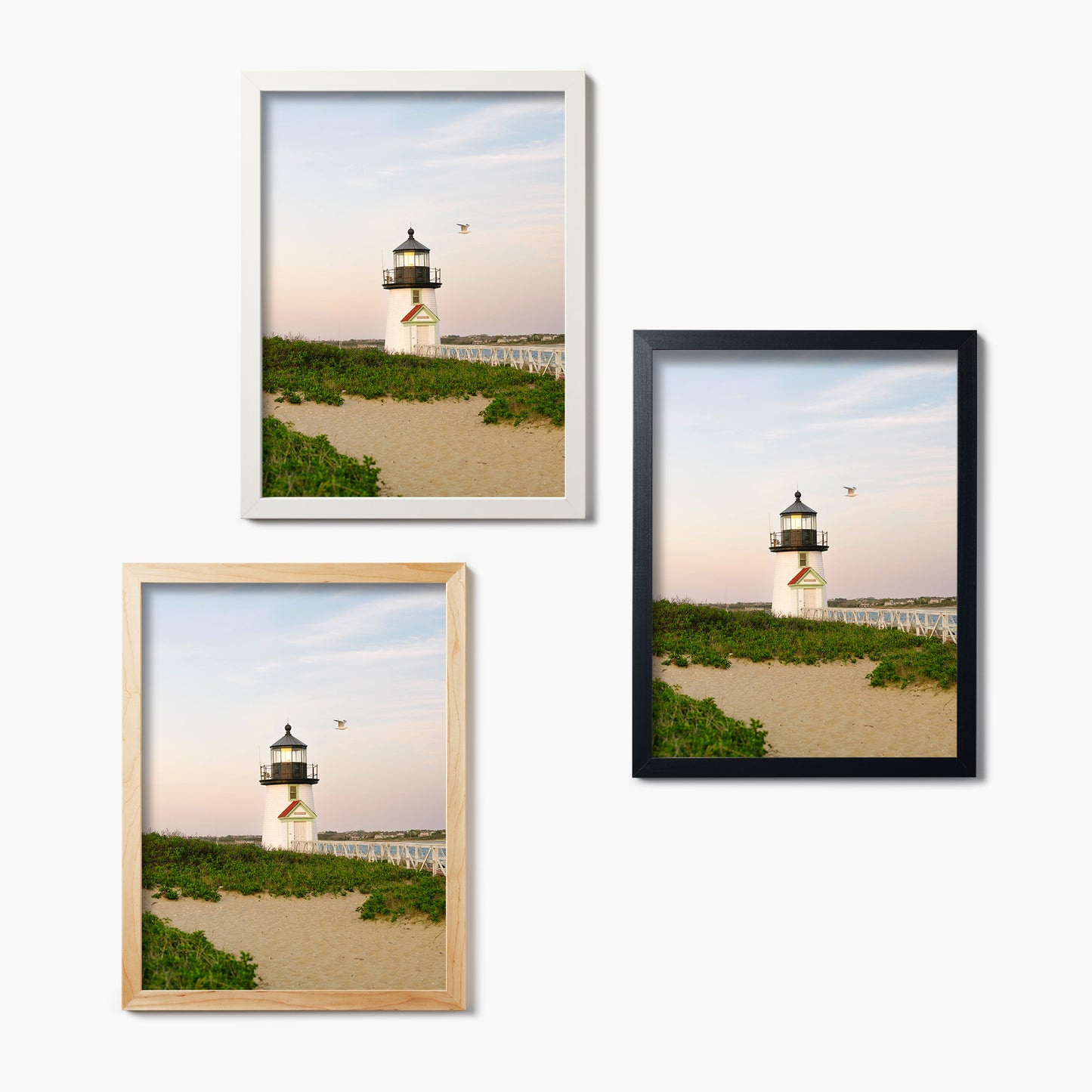 Three framed glass prints of a lighthouse on a beach with different frames.