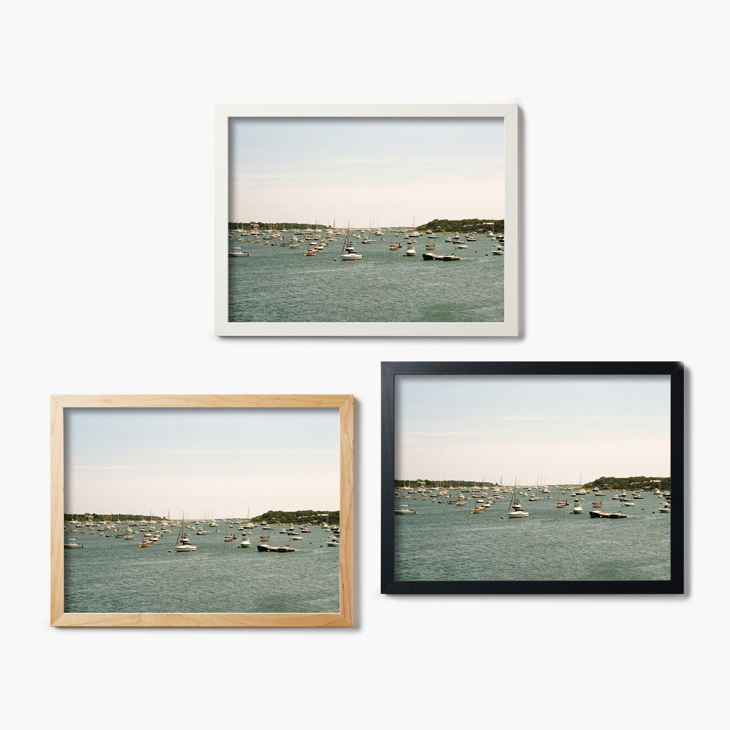 Three framed glass prints of a harbor scene with boats on a white background