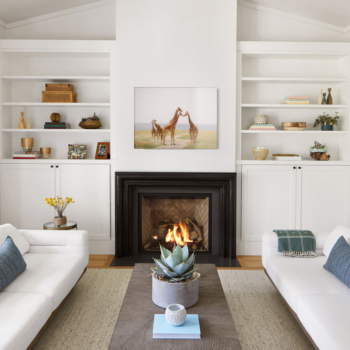 Living room with white walls, a fireplace, and a glass print of giraffes in a savannah environment.