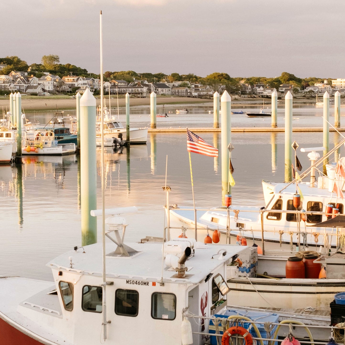 Close up of boats docked at a marina with an American flag flying, during what appears to be either sunrise or sunset.