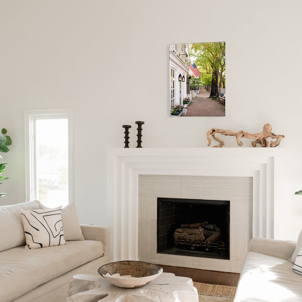 Living room with a fireplace, couch, and a glass print of a cobblestone street with an American flag flying from the buildings.