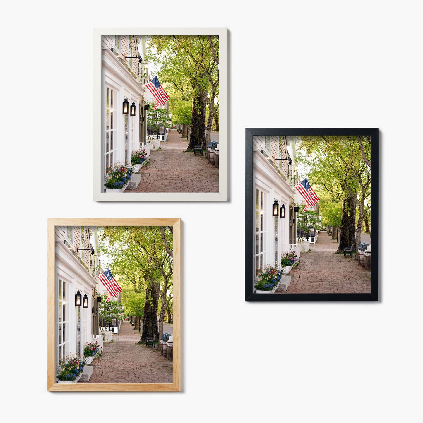 Three framed glass prints of a street scene with American flags and trees on a white background.