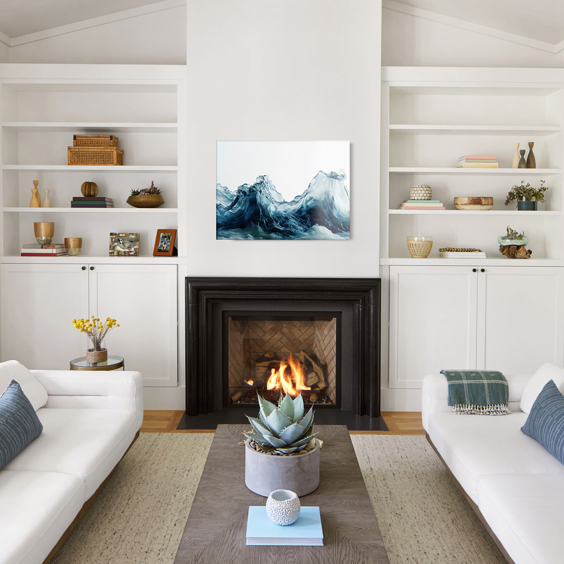 Modern living room with white walls, a fireplace, and a glass print of an abstract blue wave design.