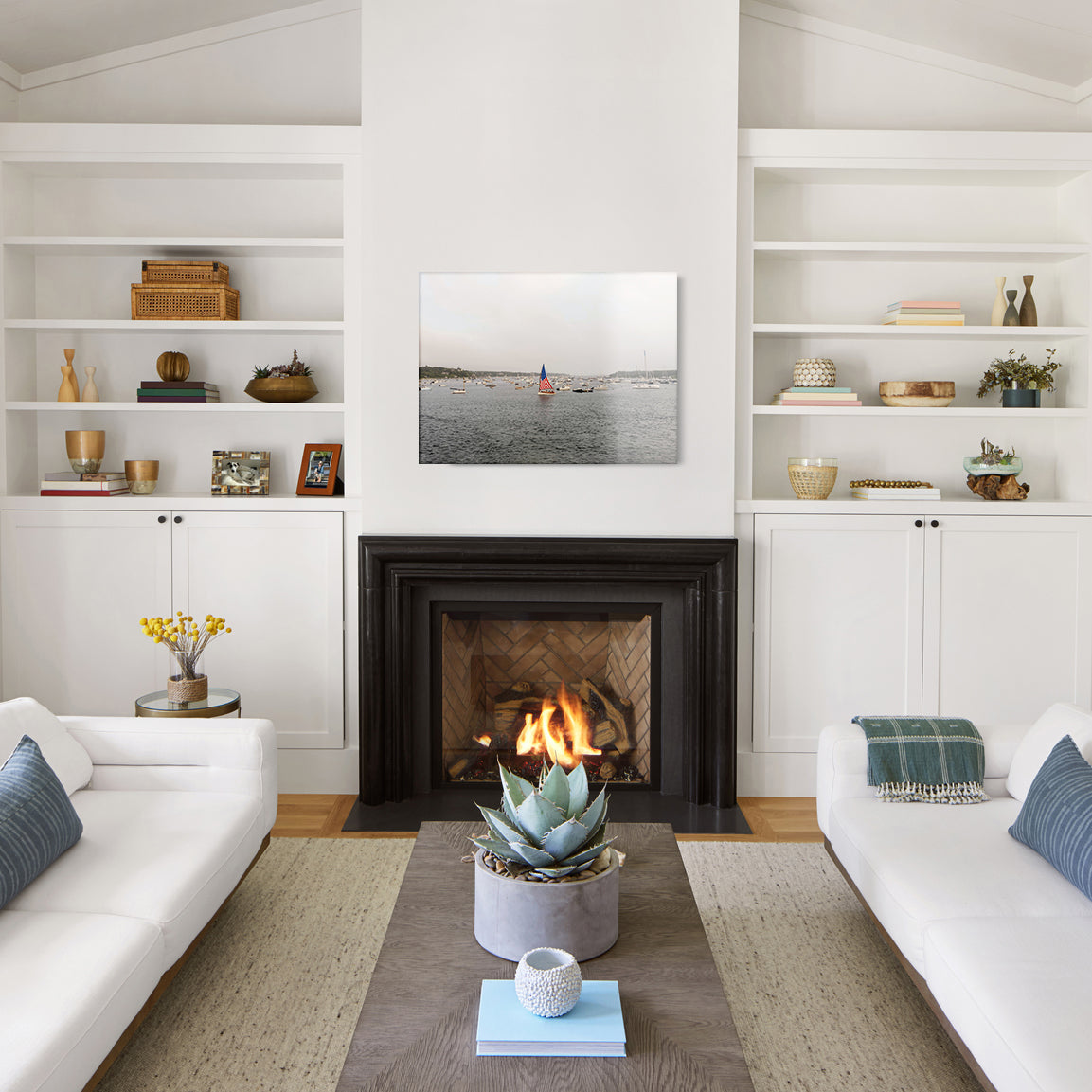 Living room with white walls, a fireplace, and a glass print with a harbor and boat flying an American flag.