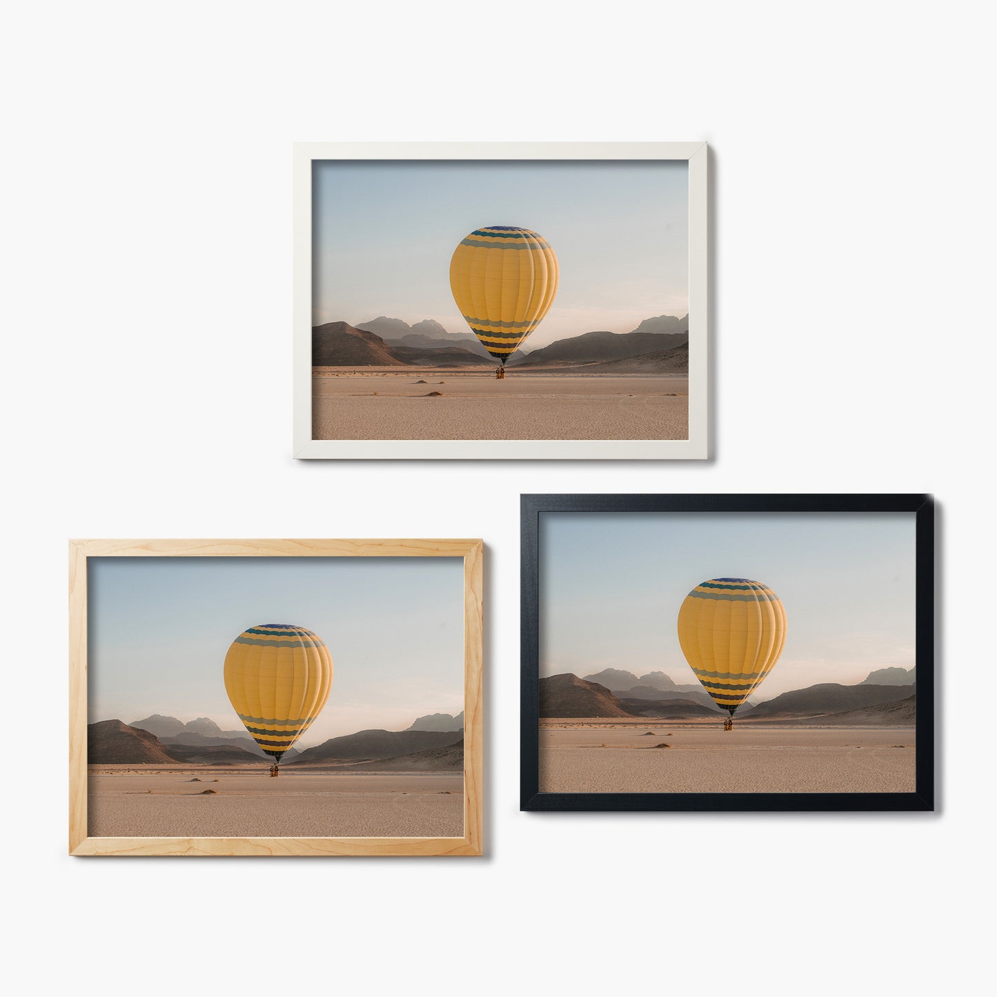 Three framed glass prints of a hot air balloon in a desert landscape.