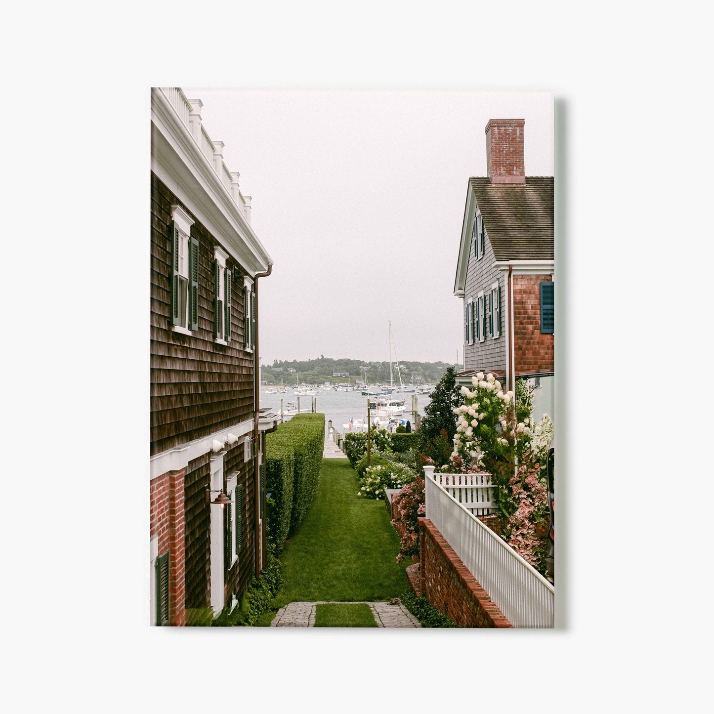 A glass print of houses with a garden and view of the sea on a cloudy day