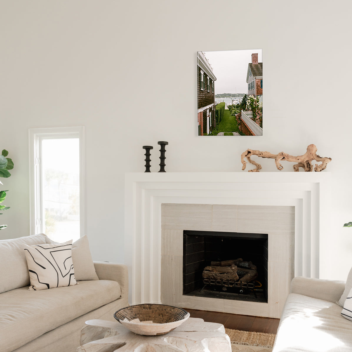 Living room with a fireplace, couch, and a glass print of a residential passthrough leading to a dock on the harbor in their backyards