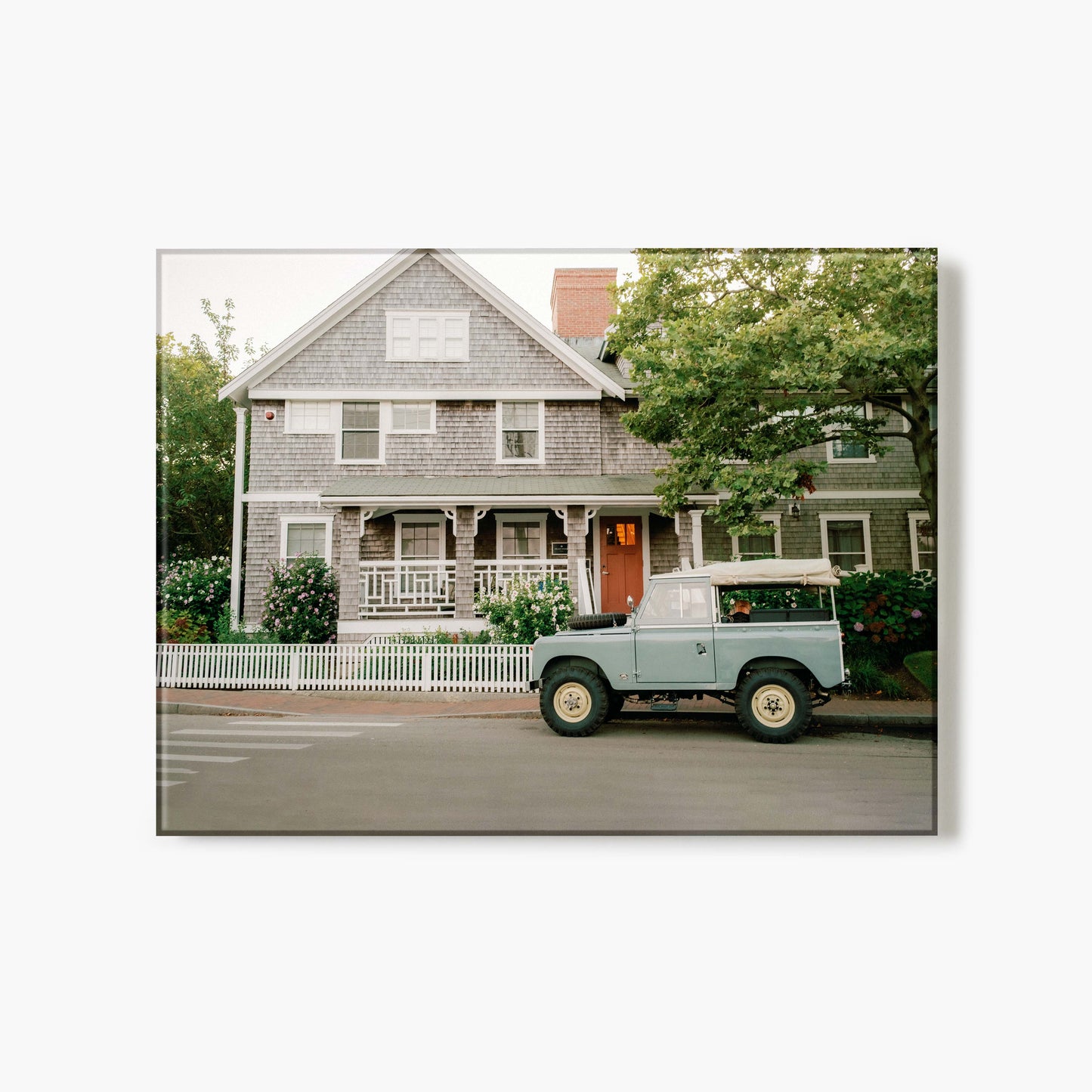 Glass print of a vintage Jeep parked in front of a house with a white picket fence.