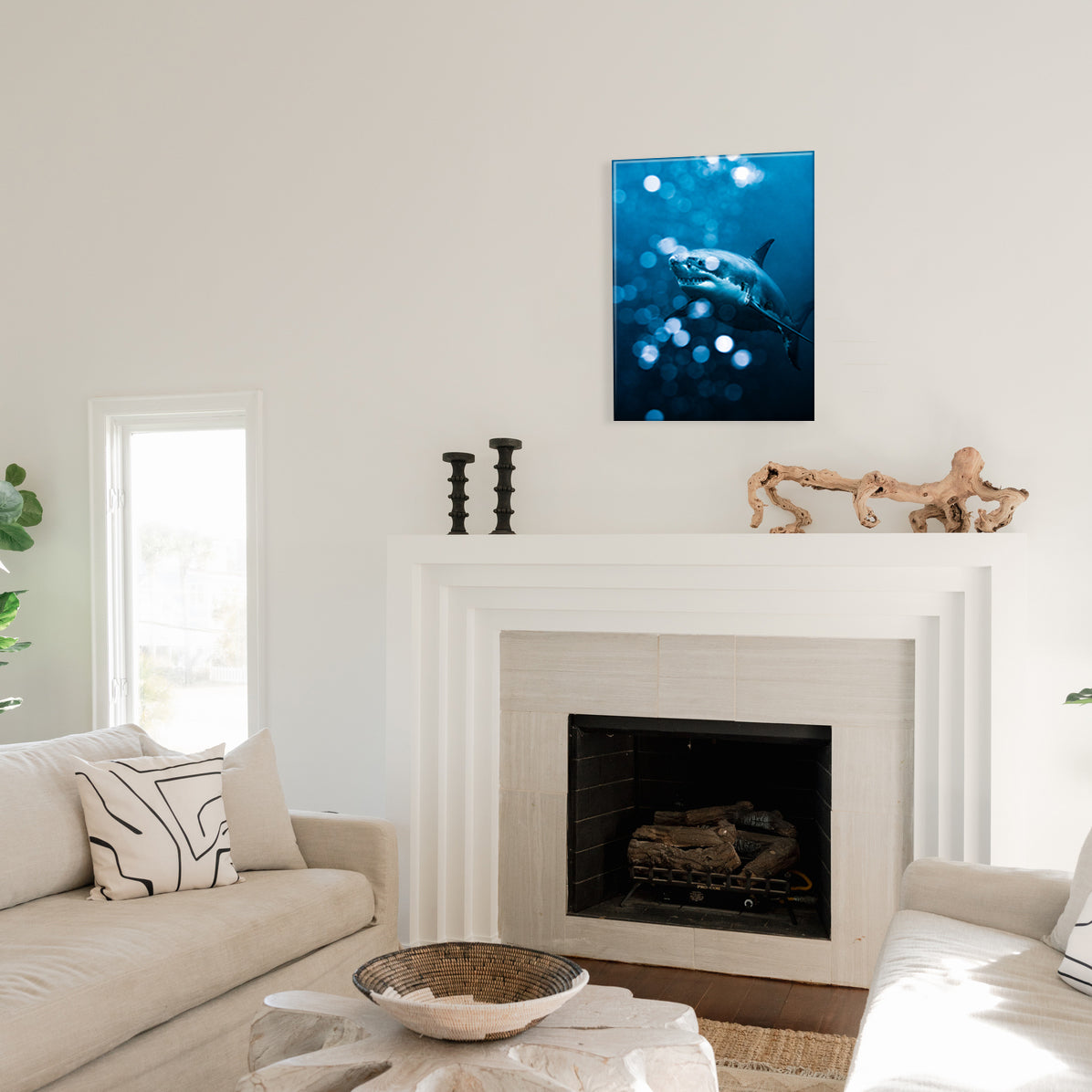 Living room with a fireplace, decorative items, and a frameless glass print of a blue shark with underwater bokeh effect.
