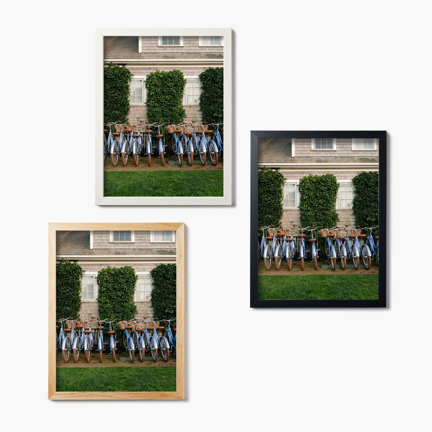 Three framed glass prints of bicycles lined up against a building with greenery.