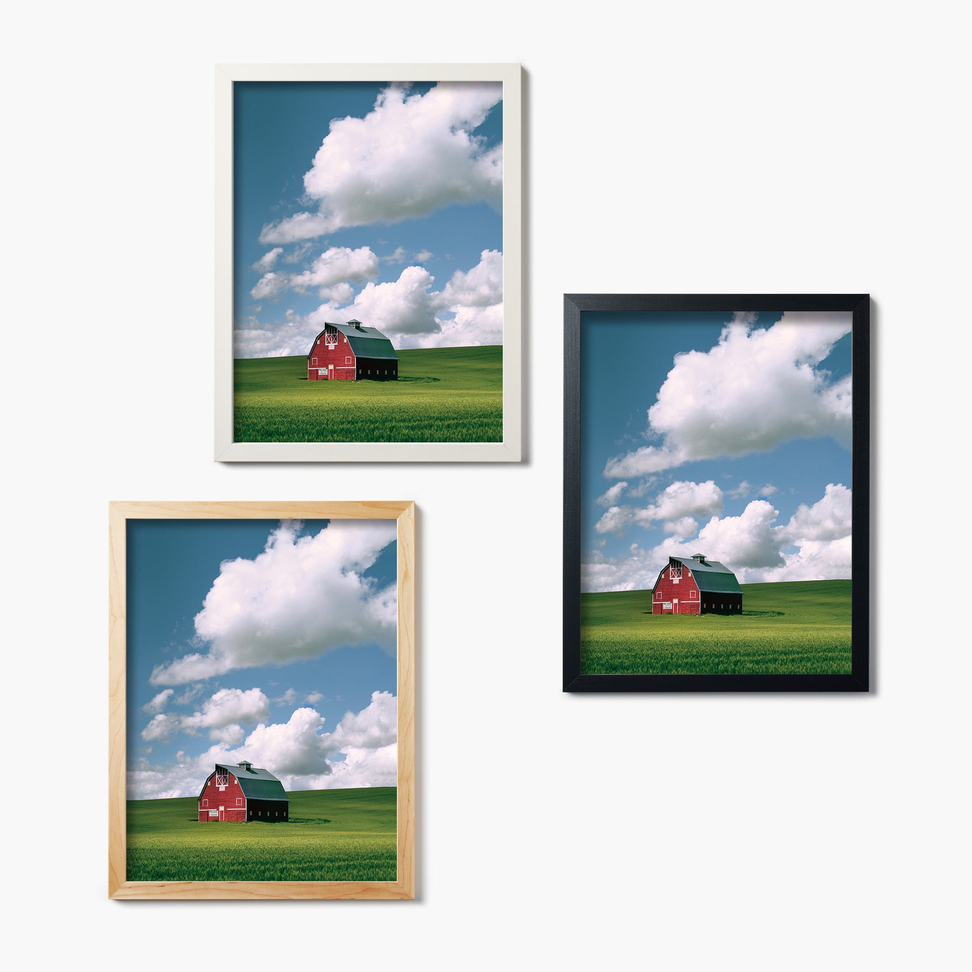 Three framed glass prints of a red barn on a green field with blue sky.