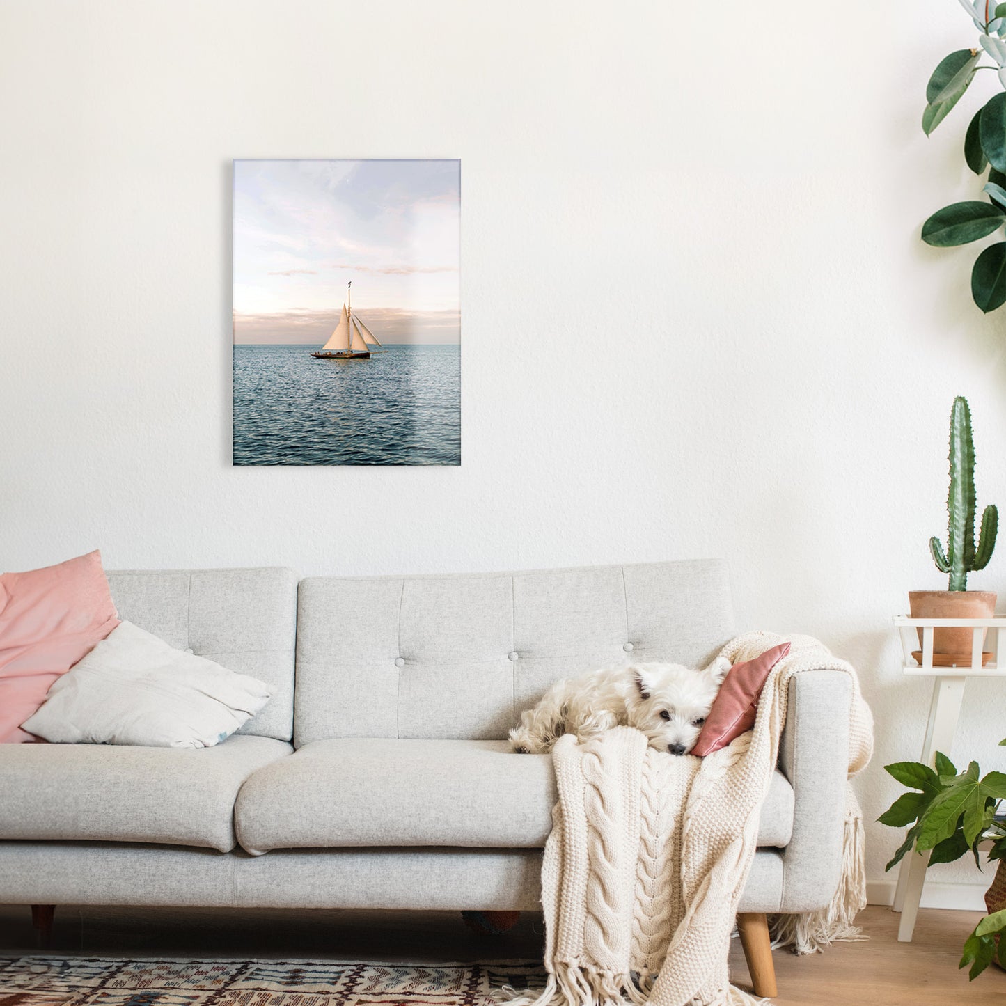Living room with a gray sofa, pink pillows, and a glass print of a sailboat on the wall.