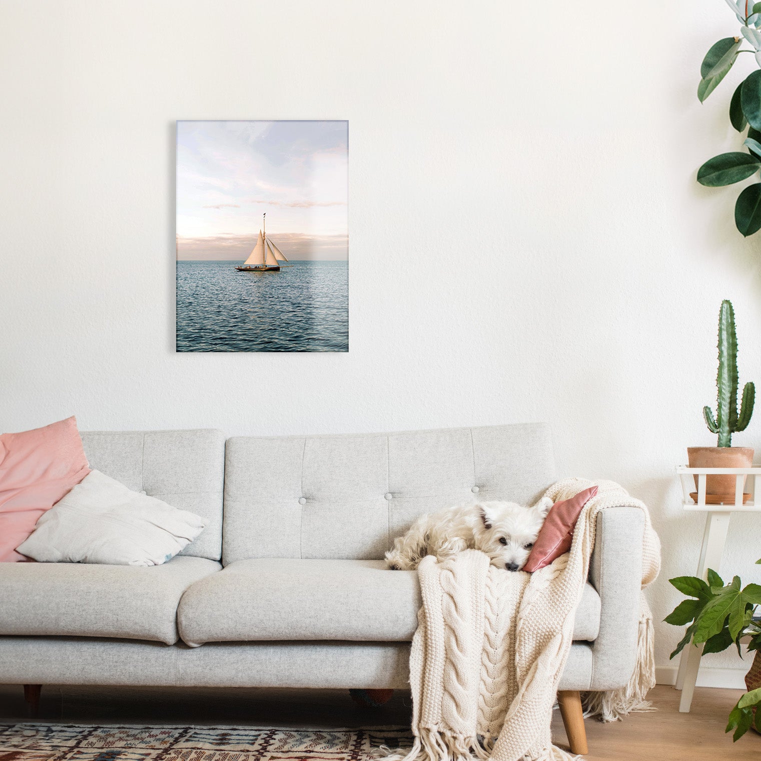 Living room with a gray sofa, pink pillows, and a glass print of a sailboat on the wall.