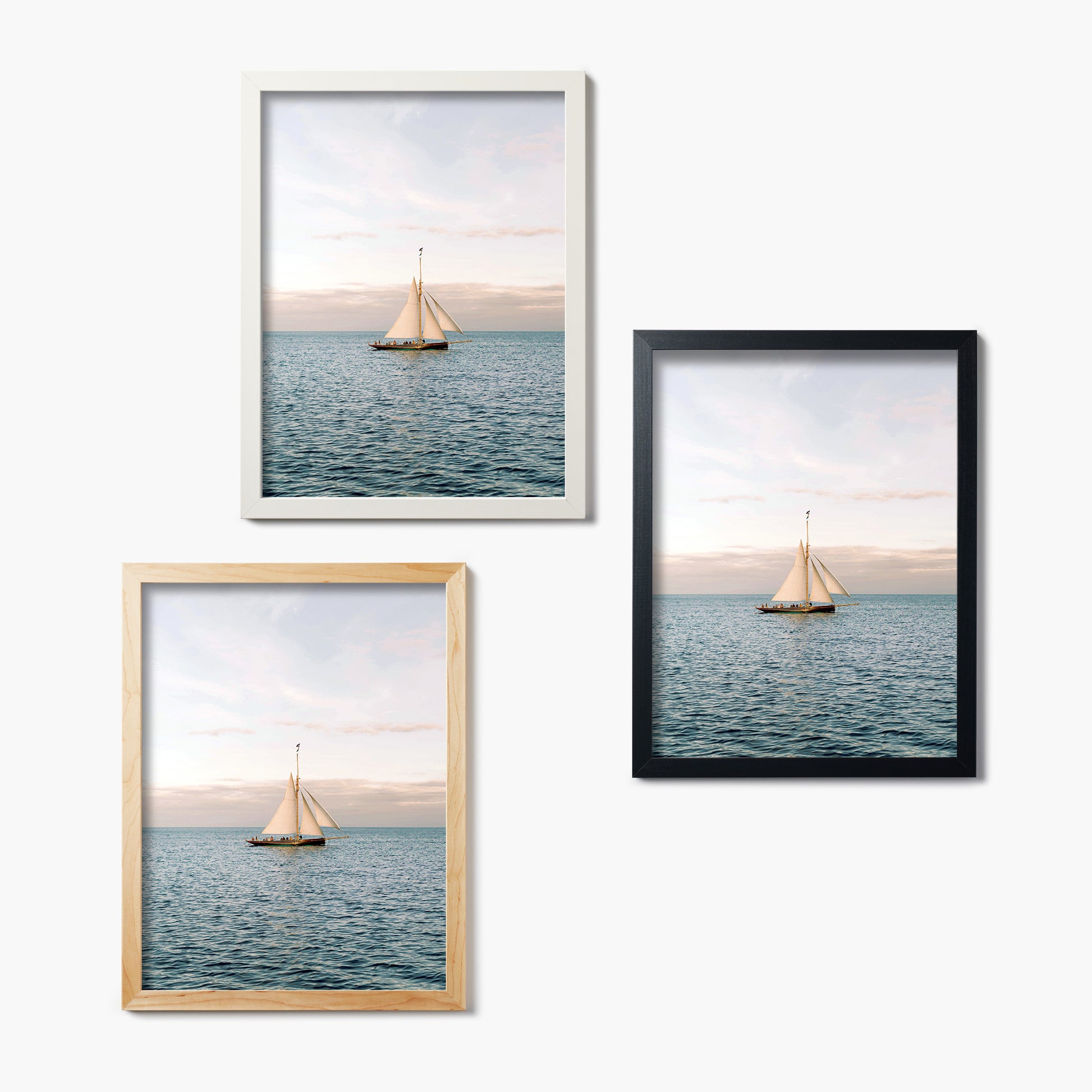 Three framed glass prints of sailboats on water with a white background