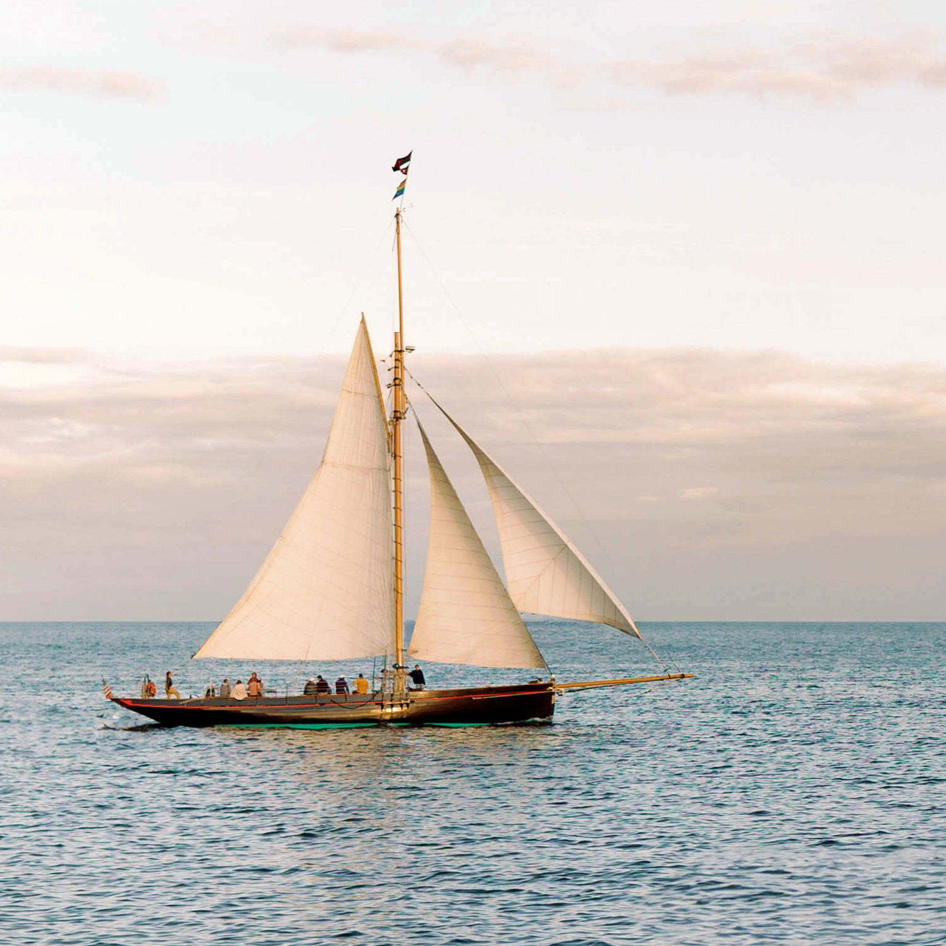Close up of sailboat with white sails on a calm sea under a cloudy sky