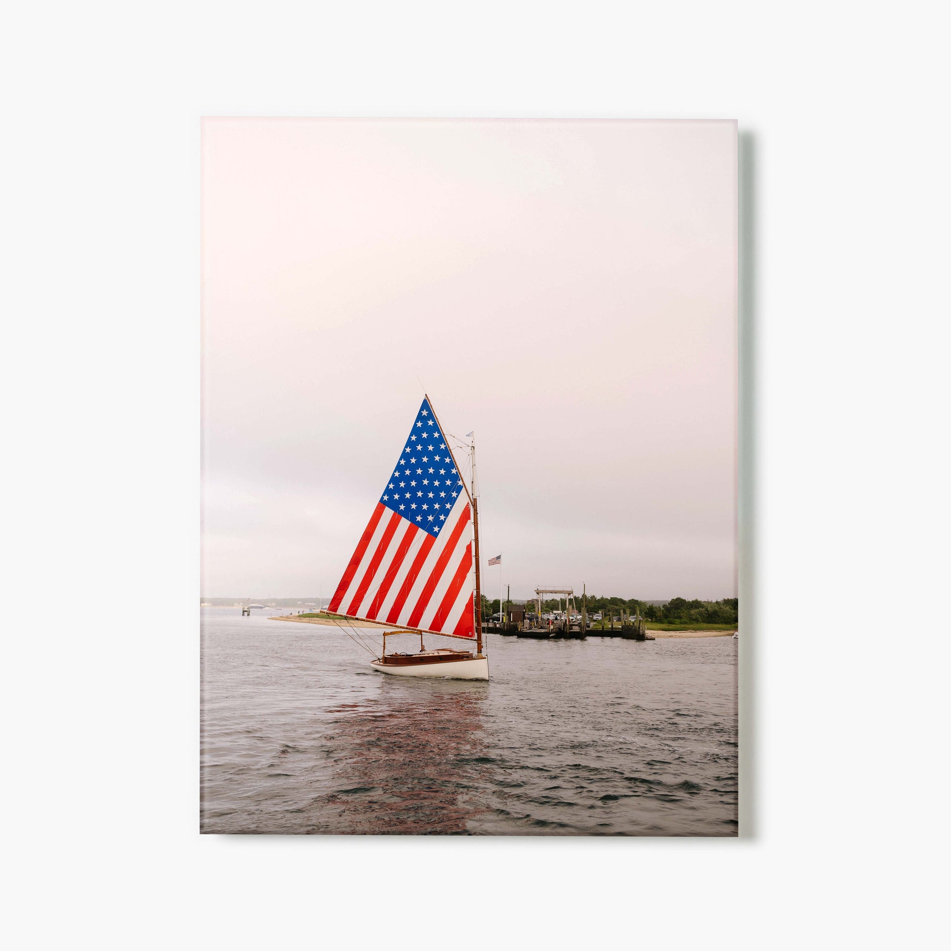 Glass print of a sailboat with an American flag on a body of water