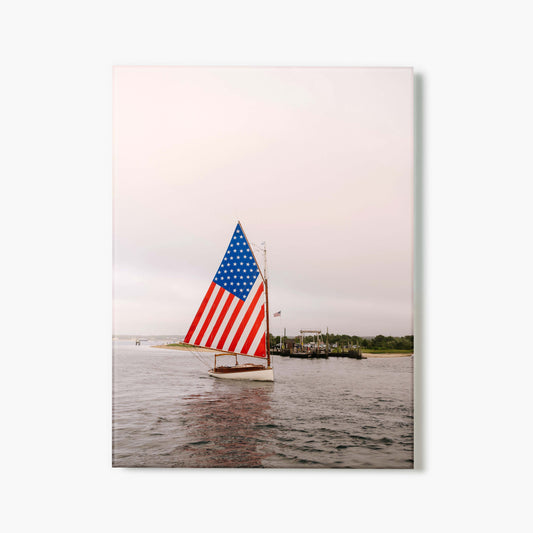 Glass print of a sailboat with an American flag on a body of water